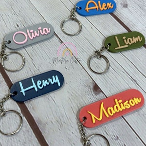 May include: Five personalized keychains with different names, each with a different color. The names are Alex, Olivia, Liam, Henry, and Madison. The keychains are made of a durable material and are perfect for adding a personal touch to your keys.