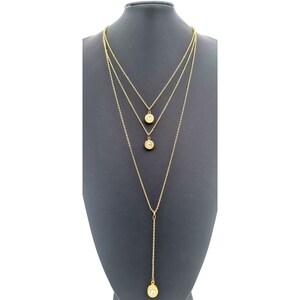 May include: A gold layered necklace with three round pendants, each featuring a clear rhinestone in the center.