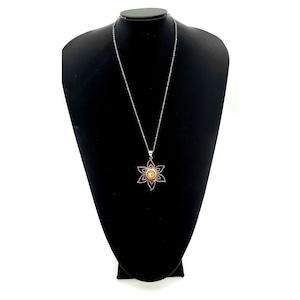 May include: A silver chain necklace with a flower pendant. The flower is made of silver and has a yellow center.
