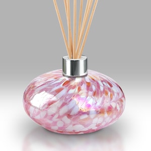 May include: Pink glass diffuser bottle with a silver lid and wooden sticks. The bottle has a speckled, iridescent finish.