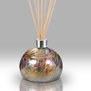 May include: A round glass diffuser bottle with a silver cap and wooden sticks. The bottle has a colorful, iridescent swirl pattern.
