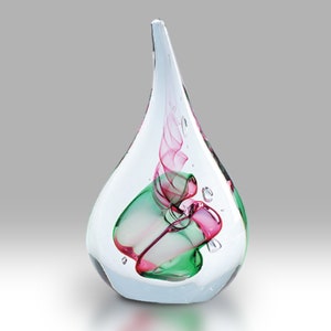 May include: A clear glass teardrop-shaped vase with a pink and green swirl inside.