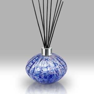 Könnte beinhalten: Ein dekorativer blauer Glasdiffusor mit silbernem Kragen, gefüllt mit schwarzen Stäbchen. Die Flasche hat ein strukturiertes, geknacktes Muster in Blau- und Weißtönen. Die Stäbchen sind fächerförmig angeordnet.