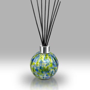 May include: A decorative glass diffuser with a round, speckled design in blue, green, and yellow. The diffuser has a silver collar and contains several black reeds. The product is designed for home fragrance.