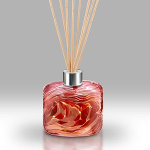 May include: A red glass diffuser bottle with a silver cap and wooden sticks. The bottle has a swirling, marbled pattern.