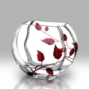 May include: A clear glass vase with a rounded, oval shape. The vase features a red floral design with leaves and stems.