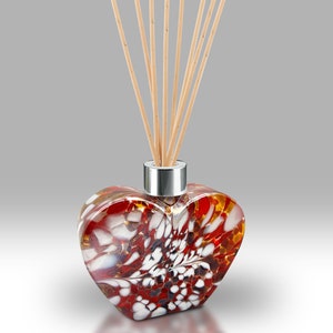 May include: A heart-shaped glass diffuser bottle with a red, white and brown marbled design. The bottle has a silver cap and wooden diffuser sticks.