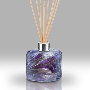 Op de afbeelding: Paarse glazen diffuserfles met een zilveren dop en houten stokjes. De fles heeft een swirl-patroon.