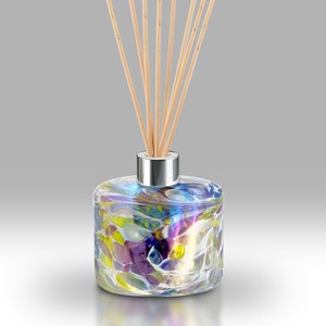 May include: A glass diffuser bottle with a colourful, abstract design. The bottle has a silver cap and is filled with a clear liquid. Wooden diffuser sticks are inserted into the bottle.