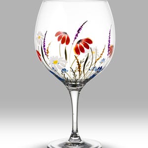 Könnte beinhalten: Ein klares Glas-Gin-Glas mit handbemaltem Design aus roten, weißen und blauen Wildblumen.