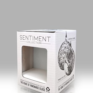 Puede incluir: Caja de cart&oacute;n blanca con una ventana troquelada, con el texto "SENTIMENT COLLECTION" y una ilustraci&oacute;n de un globo de cristal. La caja tambi&eacute;n incluye el texto "TREE OF LIFE" e informaci&oacute;n del sitio web.