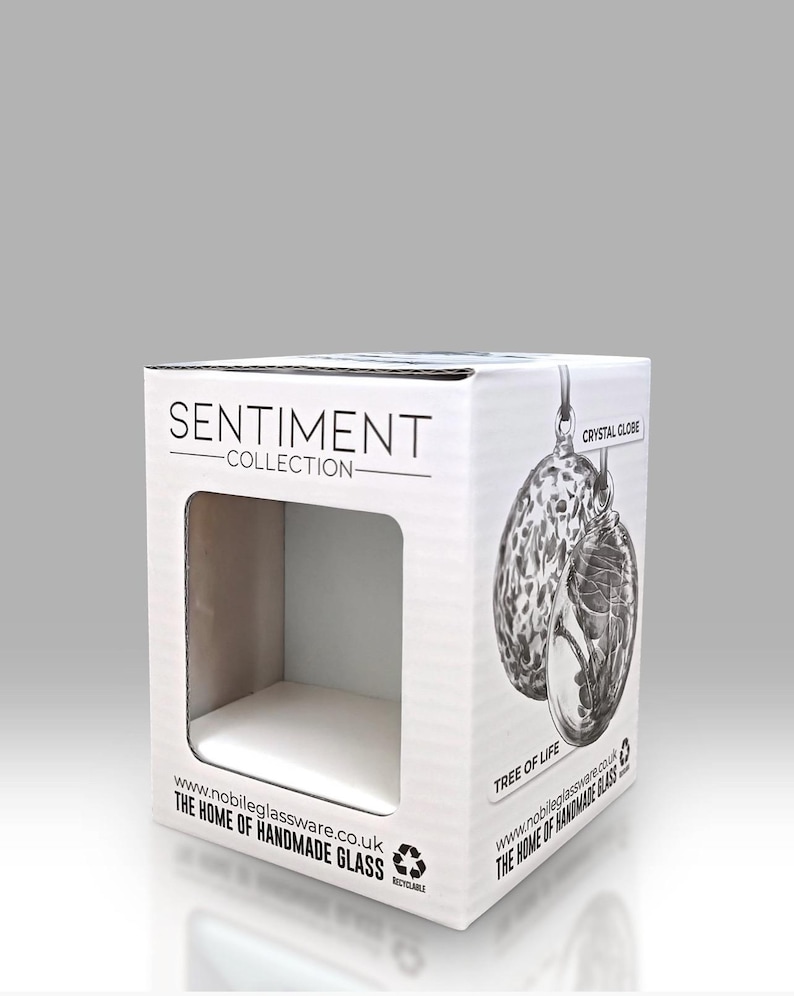 Puede incluir: Caja de cart&oacute;n blanca con una ventana troquelada, con el texto "SENTIMENT COLLECTION" y una ilustraci&oacute;n de un globo de cristal. La caja tambi&eacute;n incluye el texto "TREE OF LIFE" e informaci&oacute;n del sitio web.