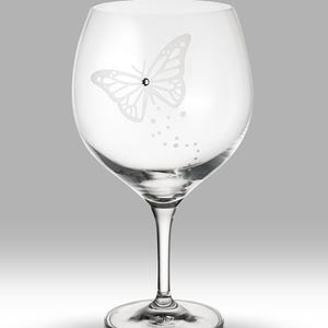 Könnte beinhalten: Ein klares Weinglas aus Glas mit einem zarten, geätzten Schmetterlingsmuster und einem einzelnen Strassstein.