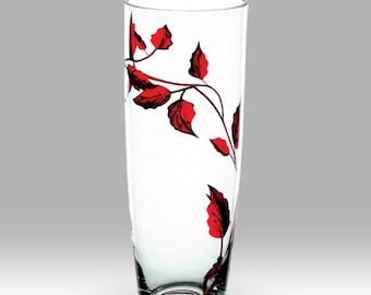 May include: A clear glass vase with a red floral design. The vase is tall and slender with a rounded bottom.