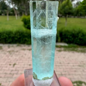 Pu&ograve; includere: Cristallo di acquamarina trasparente e rettangolare con una tonalit&agrave; azzurra. Il cristallo &egrave; montato su una base trasparente e rettangolare. Il cristallo presenta strutture interne visibili ed &egrave; sostenuto da un materiale bianco strutturato.