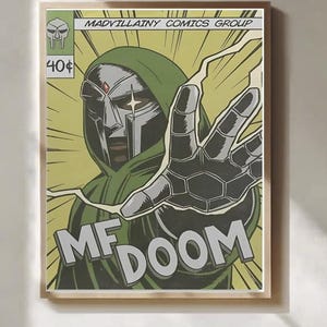 May include: A framed comic book art print of MF DOOM. The artwork shows a figure in a green hooded cloak and silver mask reaching out, with the words "MF DOOM" in large letters. The background is yellow with comic book style lines.