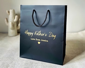 May include: Black gift bag with gold lettering that says "Happy Father's Day Love from Jessica" and a gold heart.