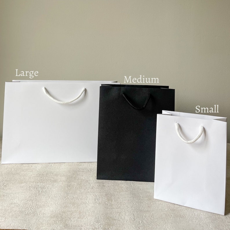 Luxury Personalised Team Bride Gift Bag and white sticker with gold foil writing and sticker. Writing says team bride with the option for adding a name and a date or location. Perfect for hen party favours and hen party gifts for your Team Bride.