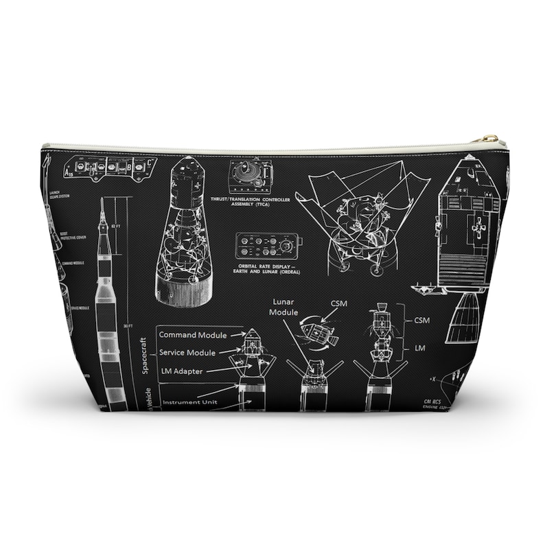 May include: Black wash bag with a white blueprint design of a spacecraft, including the command module, service module, and lunar module. The bag has a gold zip and is suitable for storing toiletries.