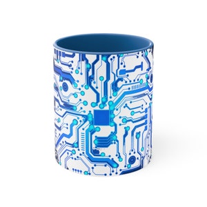May include: A white ceramic mug with a blue rim and a blue circuit board design. The design features a blue and white circuit board pattern with a blue square in the center.