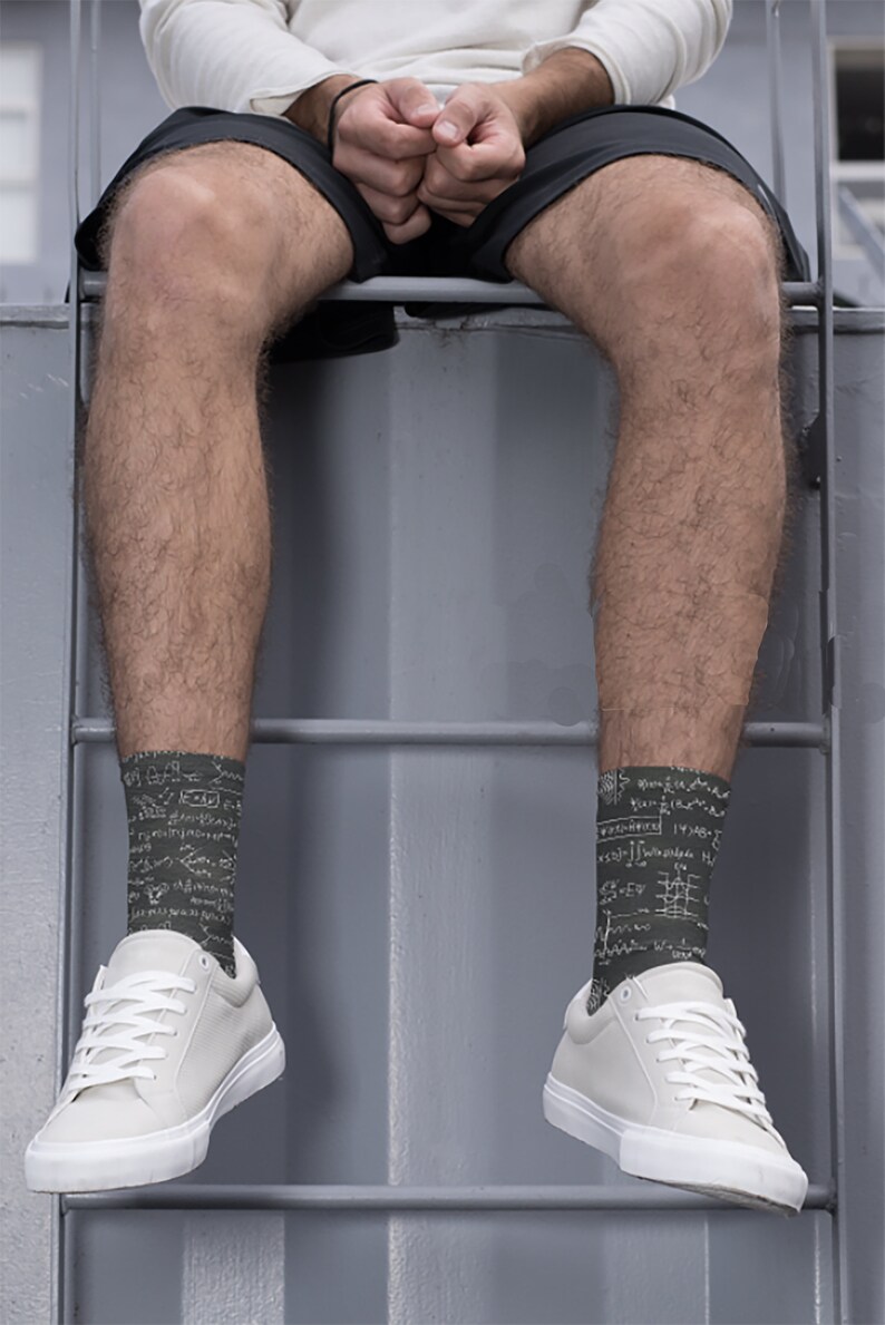 K&ouml;nnte beinhalten: Eine Person tr&auml;gt dunkelgr&uuml;ne Socken mit wei&szlig;en mathematischen Gleichungen und wei&szlig;en Turnschuhen. Die Socken sind der Mittelpunkt, wobei die Gleichungen die gesamte Socke bedecken. Die Turnschuhe sind wei&szlig; mit wei&szlig;en Schn&uuml;rsenkeln.