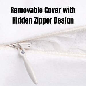 May include: A white zipper with a white pull tab. The zipper is partially open, revealing a white fabric with a small, white, dotted pattern. The text "Removable Cover with Hidden Zipper Design" is visible above the zipper.