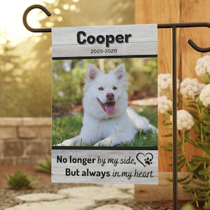 May include: A white garden flag with a photo of a white dog and the text "Cooper 2005-2020" at the top. The flag also has the text "No longer by my side, But always in my heart" with a paw print and heart.