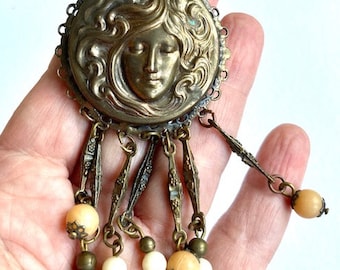 Antique Art Nouveau Czech large stamped brass round brooch pin with pendants; image of a woman&#39;s face in the style of Alphonse Mucha