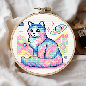May include: A cross-stitch pattern of a cat with a galaxy design. The cat is sitting with its tail curled around its body. The galaxy design is in shades of blue, pink, and yellow. There are stars and planets in the background.
