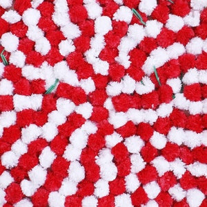 K&ouml;nnte beinhalten: Eine dichte Anordnung kleiner, runder, ger&uuml;schter Pompons in abwechselnd leuchtend roten und wei&szlig;en Farben. Die Pompons sind in einem sich wiederholenden Muster eng zusammengesetzt, wobei d&uuml;nne gr&uuml;ne Drahtstiele in Abst&auml;nden sichtbar sind.
