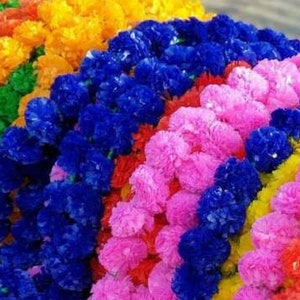 K&ouml;nnte beinhalten: Eine Ansammlung k&uuml;nstlicher Blumengirlanden mit dichten, ger&uuml;schten Bl&uuml;tenbl&auml;ttern in leuchtenden Farben wie Blau, Pink, Gelb, Orange, Rot und Gr&uuml;n. Die Str&auml;nge sind in parallelen Reihen angeordnet und bilden ein buntes Arrangement aus Kunstblumen.