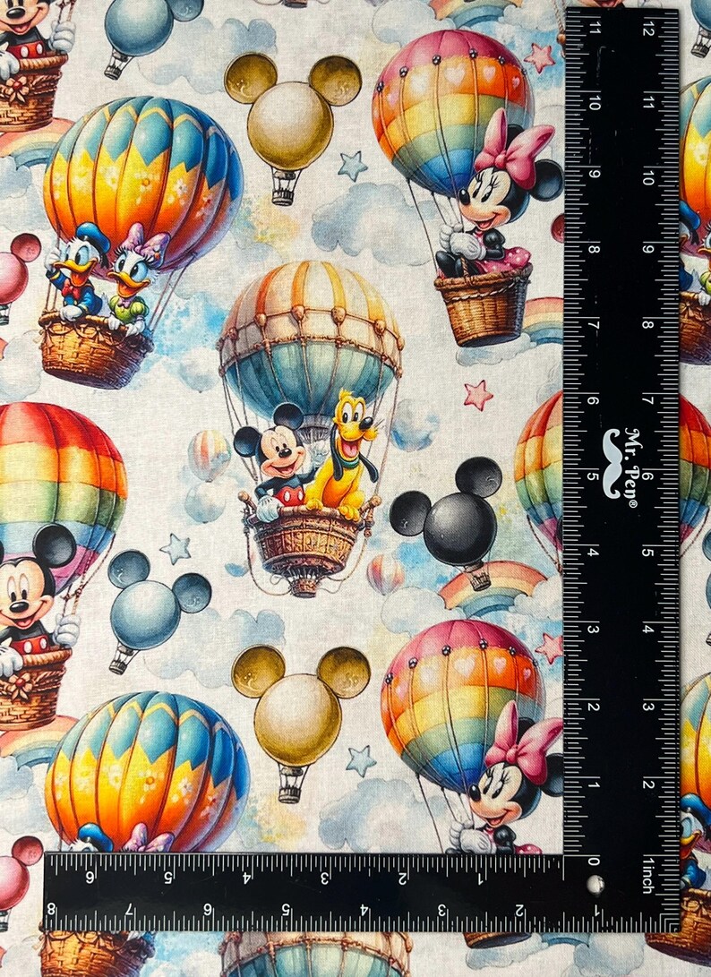 May include: Fabric featuring a repeating pattern of Disney characters in hot air balloons. Mickey Mouse, Minnie Mouse, Donald Duck, and Pluto are seen in colorful balloons against a cloudy sky background. The balloons have rainbow and striped designs.
