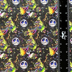 May include: A black fabric with a repeating pattern of a green and purple character with a stitched face, a black and white stitched face, and other colorful details. The fabric is measured with a ruler in inches.