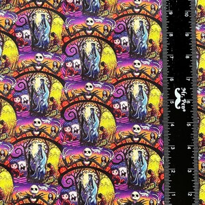 May include: A colorful fabric with a repeating pattern of Jack Skellington and Sally from the Nightmare Before Christmas. The pattern is on a purple background with yellow, orange, and black accents. The fabric is measured with a ruler in inches.