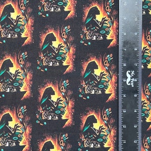 May include: A black fabric with a repeating pattern of a woman's silhouette in a teal dress, holding a glowing orb. The background is a dark, starry sky with orange and yellow accents.