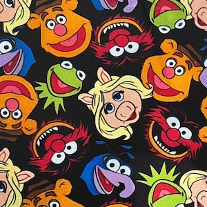 May include: A black background is covered with colorful cartoon character faces. The characters include Kermit the Frog, Miss Piggy, Fozzie Bear, Animal, and others. The faces are in various colors, including green, orange, red, and blue.