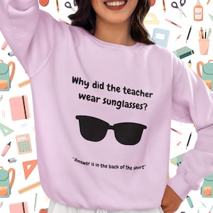 Funny Teacher Sweatshirt, "Bright Students" Graphic Pullover, Unisex Cozy Apparel with Quote: Why did the teacher wear sunglasses? a black sunglasses is designed in the apparel. *Answer is in the back of the shirt - Because her students sere so bright! Female model wearing lavender color sweatshirt.