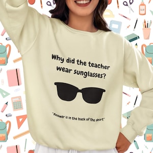 Funny Teacher Sweatshirt, "Bright Students" Graphic Pullover, Unisex Cozy Apparel with Quote: Why did the teacher wear sunglasses? a black sunglasses is designed in the apparel. *Answer is in the back of the shirt - Because her students sere so bright! Female model wearing bone color sweatshirt.