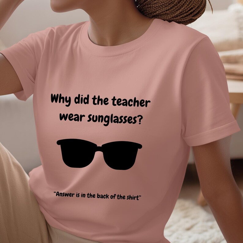 Funny Teacher T-Shirt, "Bright Students" Graphic Tee, Unisex Shirt with Quote: Why did the teacher wear sunglasses? a black sunglasses is designed in the apparel. *Answer is in the back of the shirt - Because her students sere so bright! Female model wearing blossom color t-shirt.