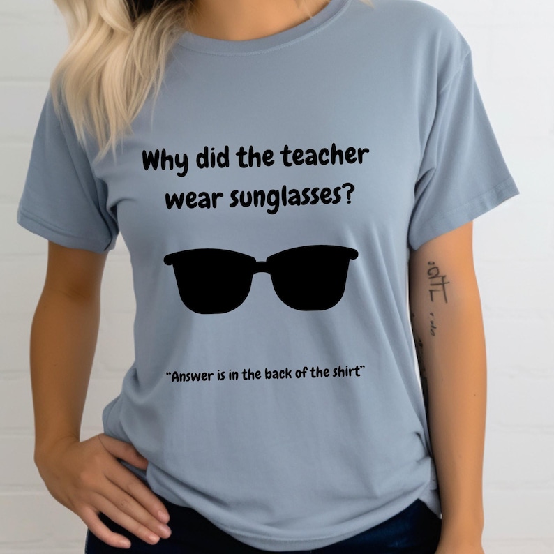 Funny Teacher T-Shirt, "Bright Students" Graphic Tee, Unisex Shirt with Quote: Why did the teacher wear sunglasses? a black sunglasses is designed in the apparel. *Answer is in the back of the shirt - Because her students sere so bright! Female model wearing blue jean color t-shirt.
