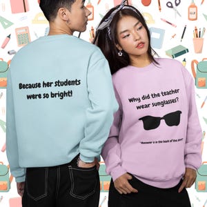 Funny Teacher Sweatshirt, "Bright Students" Graphic Pullover, Unisex Cozy Apparel with Quote: Why did the teacher wear sunglasses? a black sunglasses is designed in the apparel. *Answer is in the back of the shirt - Because his students sere so bright! Female model wearing lavender color sweatshirt. male model wearing a sky blue color sweatshirt.