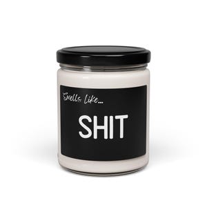 May include: A white candle jar with a black label that reads "Smells like... SHIT".