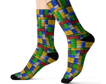 Könnte beinhalten: Ein Paar bunte Socken mit einem sich wiederholenden Muster aus bunten Lego-Steinen. Die Socken sind an Zehen und Ferse schwarz.