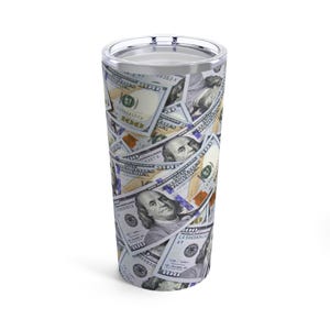 May include: A stainless steel tumbler with a design of US dollar bills. The tumbler is silver with a black lid.