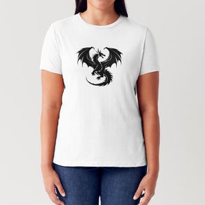 May include: A white t-shirt featuring a black silhouette of a dragon with its wings outstretched.