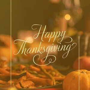 Può includere: Un primo piano di una tavola da pranzo del Ringraziamento con una pentola di verdure arrostite, una zucca e il testo "Happy Thanksgiving" in un carattere decorativo.