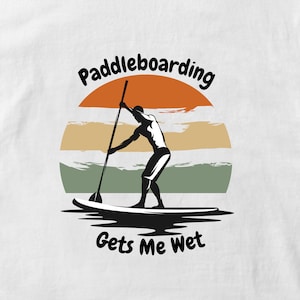 May include: A silhouette of a person paddleboarding with a sunset in the background. The text "Paddleboarding Gets Me Wet" is below the image.