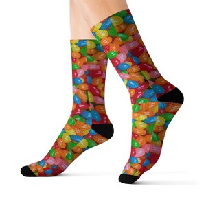 May include: A pair of colorful socks with a jelly bean pattern. The socks are black at the ankle and have a bright, multi-colored jelly bean design.