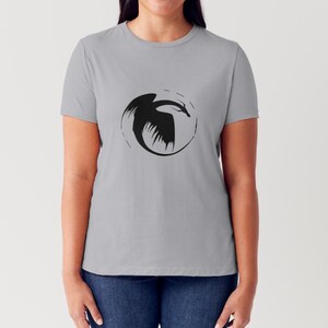 May include: A grey t-shirt with a black silhouette of a dragon in a circle on the front.