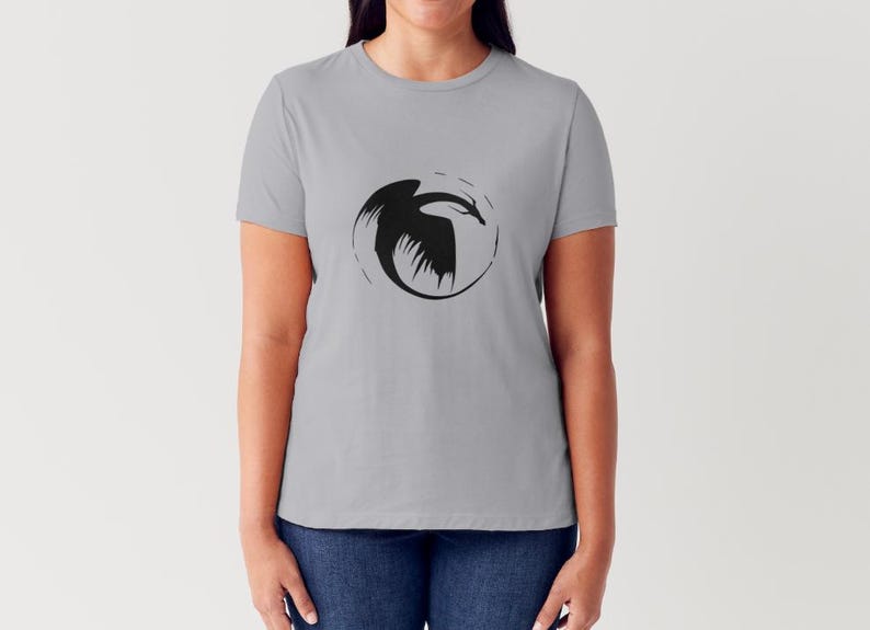 May include: A grey t-shirt with a black silhouette of a dragon in a circle on the front.